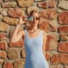 Model wearing Mika modest swim romper in Puffy Seashell Ocean, featuring a scoop neckline, fitted shorts and textured seashell fabric while walking along a coastal street.